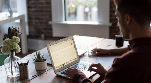 A man works on his laptop at a bright desk
