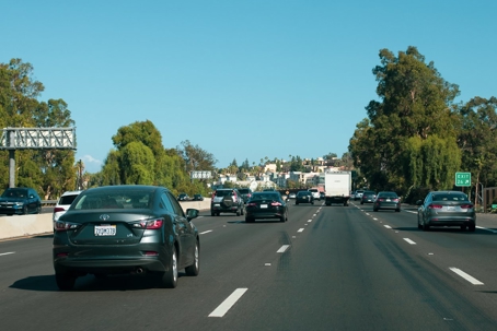 Cars drive on a multi-lane highway on a clear day.