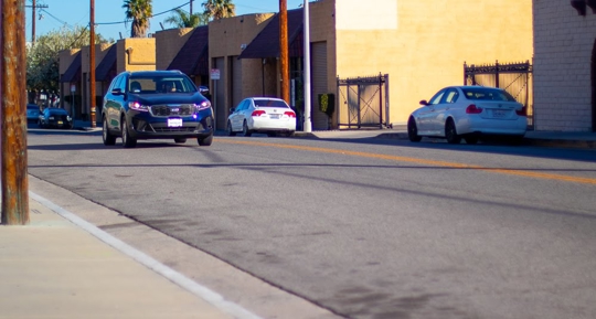 A street view showcases various cars parked