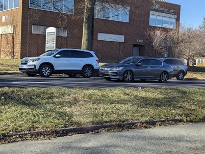 Three cars parked by a brick building