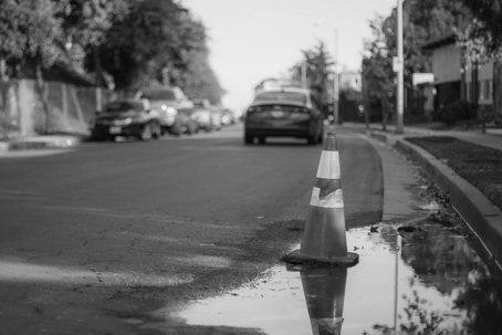traffic cone sits next to a puddle