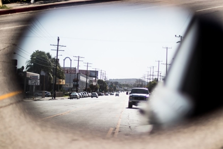 A rearview mirror frames a sunlit street