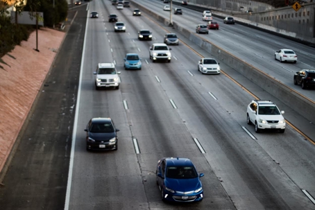 Multiple cars drive on a busy freeway