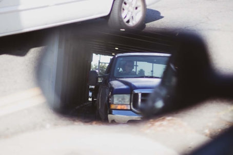 A blue truck driving through a dark tunnel as seen in a car's side mirror