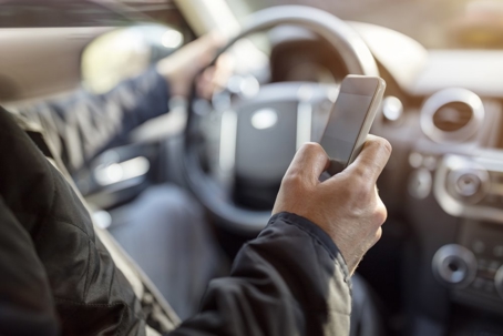 A driver holds a cell phone while driving