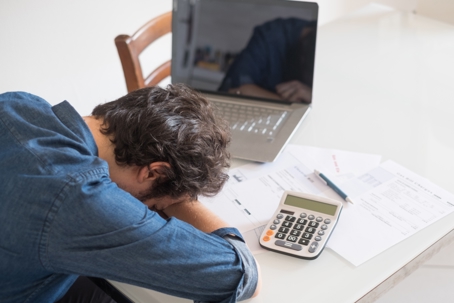 A frustrated person rests their head on a desk