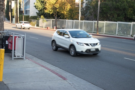 white Nissan SUV driving on a city street