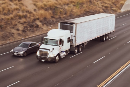 A semi-truck and car travel on a highway