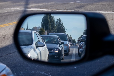 A side-view mirror shows traffic behind a car