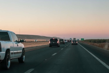 Cars fill a highway during a pastel sunset.