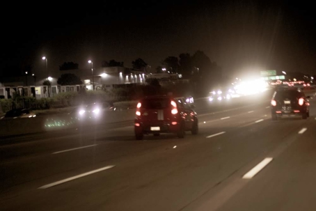 Vehicles drive on a busy highway at night
