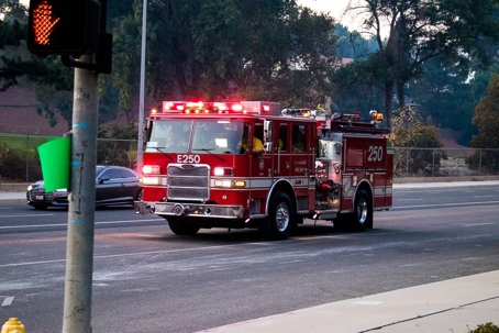 A red fire engine speeds down a street with lights flashing